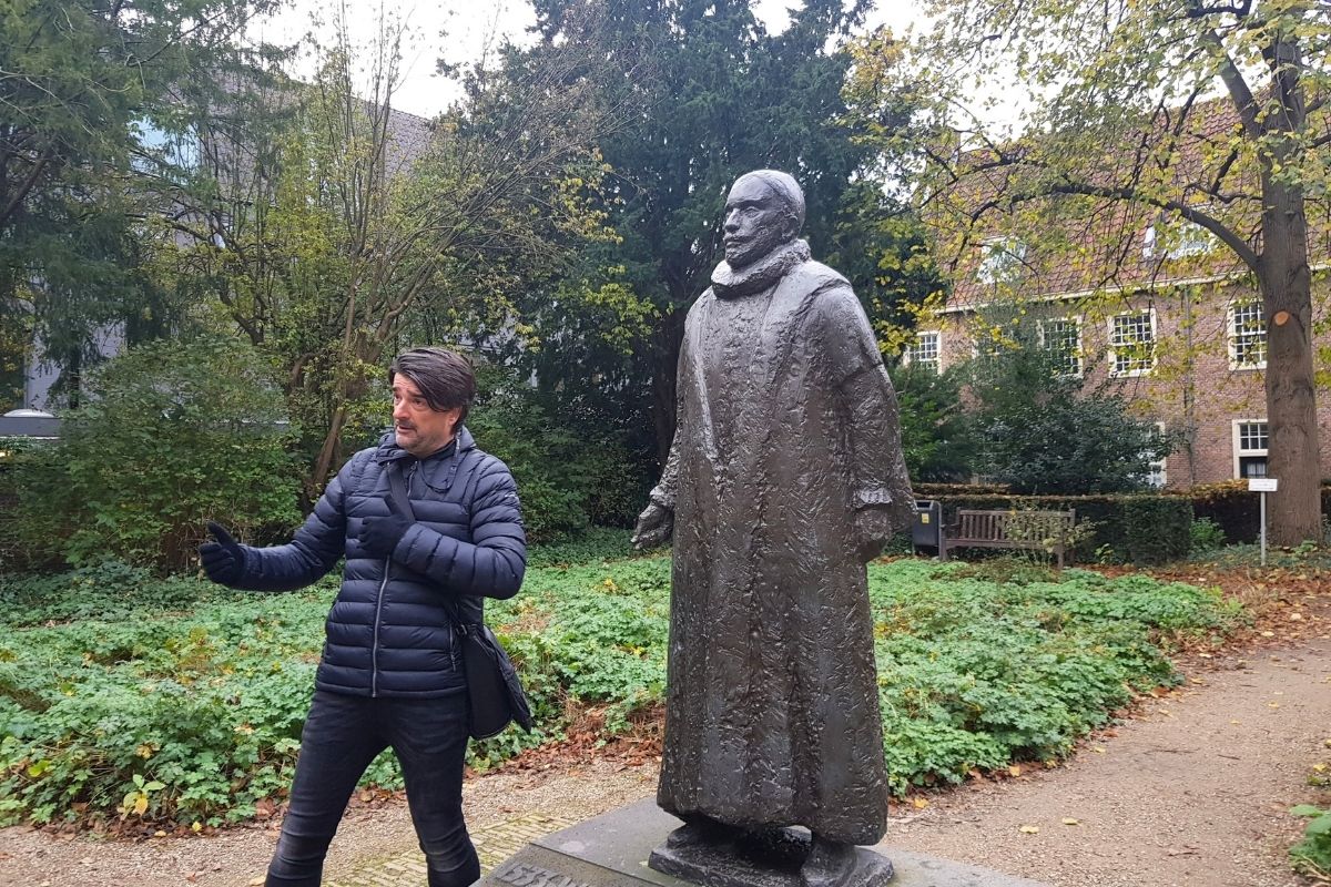 Stadsgids André van de Vooren tijdens een rondleiding in het centrum van Delft - bij het standbeeld van Willem van Oranje